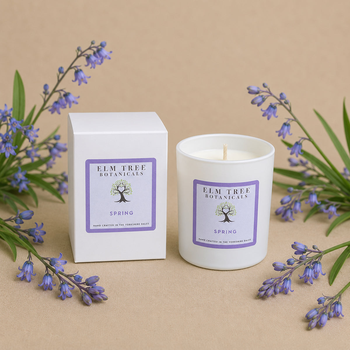 Candle and packaging with 'Elm Tree Botanicals' branding on a beige background with flowers.