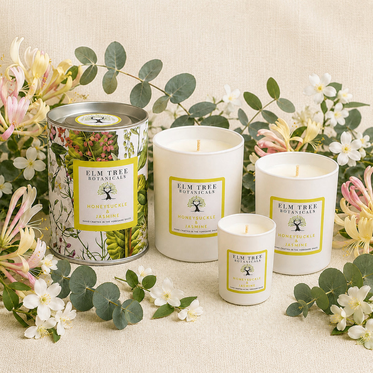 Elm Tree Botanicals candles and a tin surrounded by flowers on a beige background